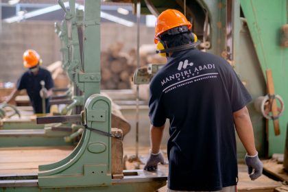 Trabalhadores usando equipamentos de proteção operam máquinas em uma fábrica.