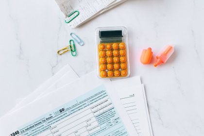 Formulários fiscais e uma calculadora organizados sobre uma mesa de escritório.